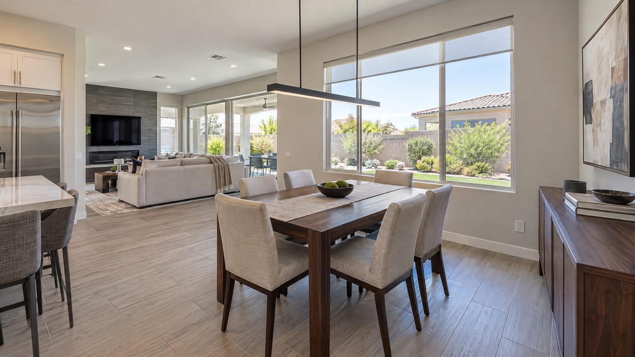 An open dining room and kitchen with a large window onto a walled desert backyard