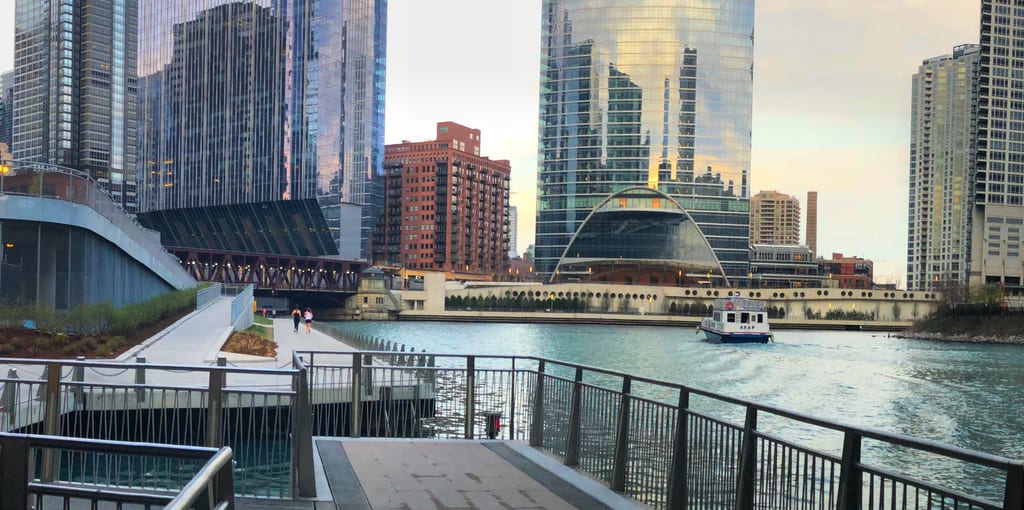 Chicago Riverwalk steps and a boat on the river beneath downtown buildings