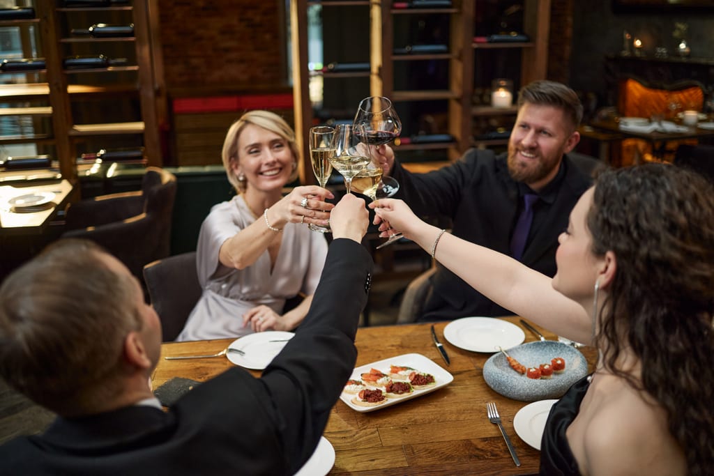 Friends raising wine glasses together around a restaurant table