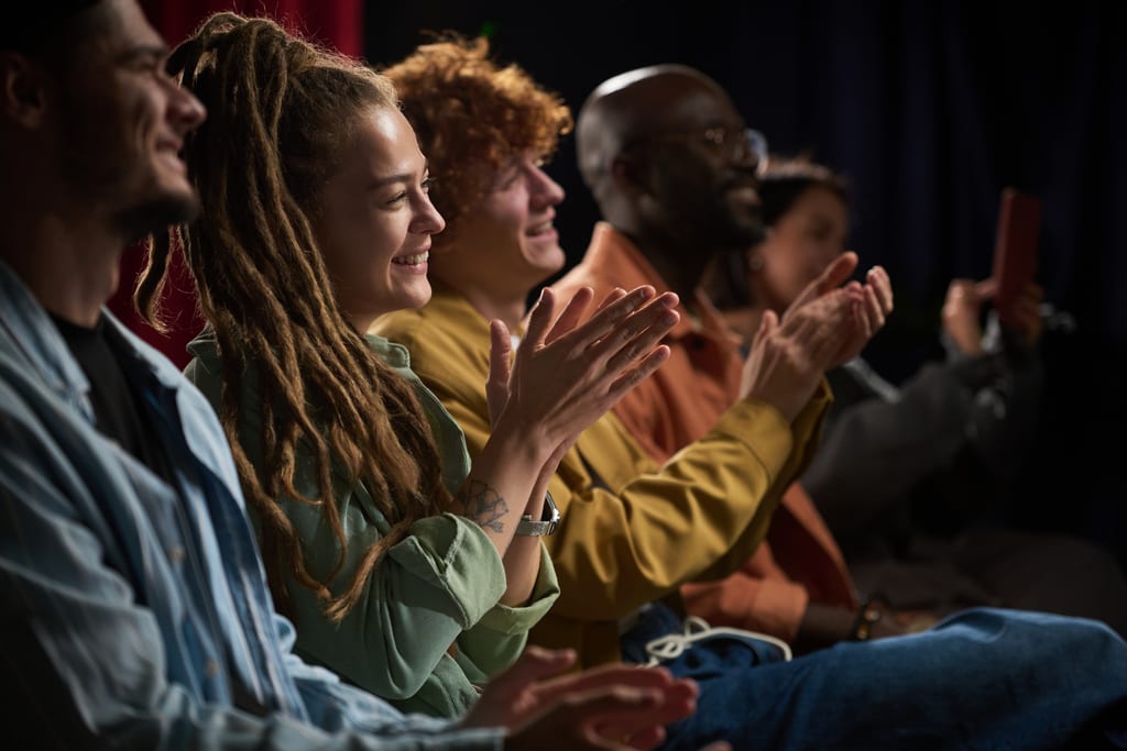 Smiling audience members applauding from their seats