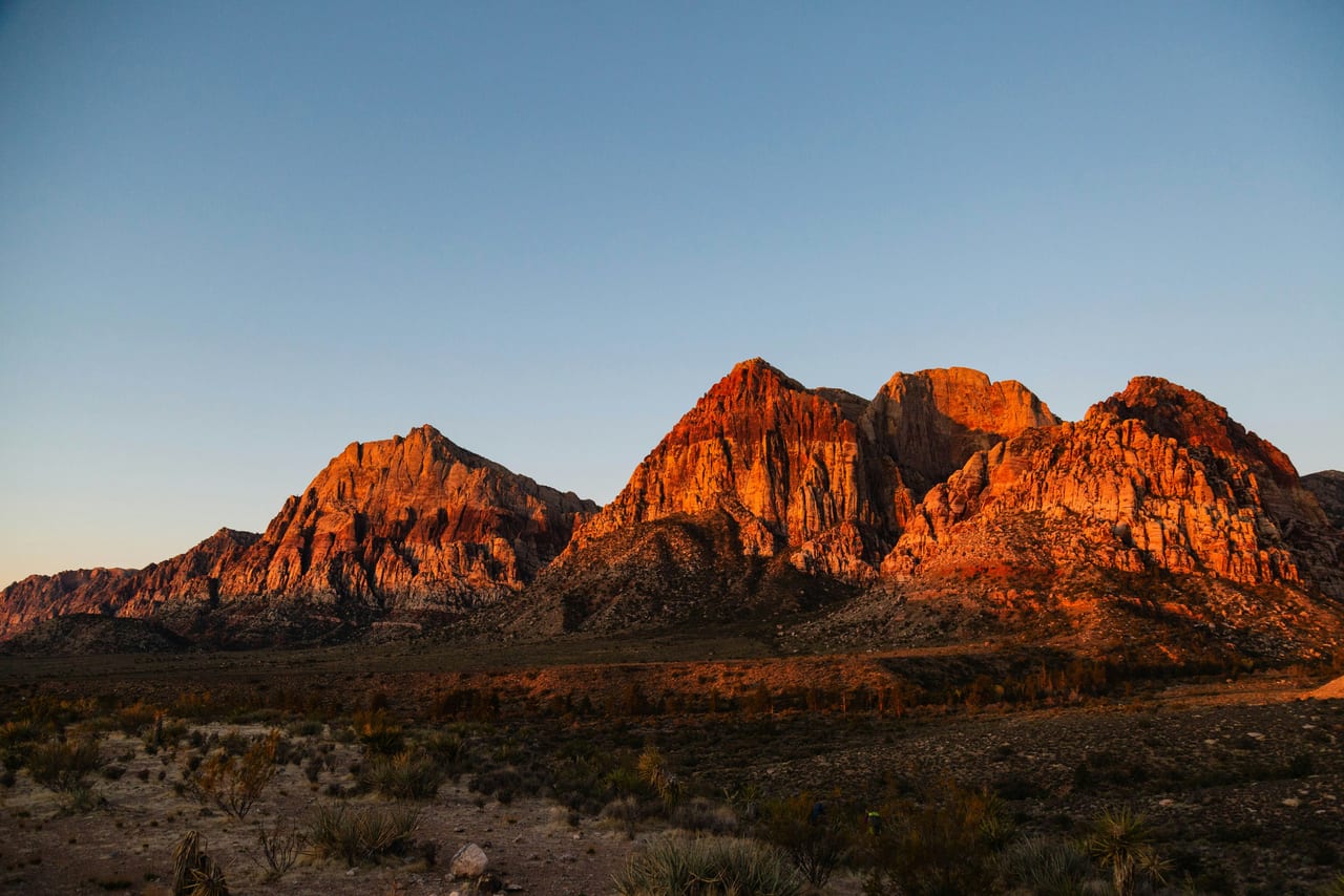 Red sandstone peaks lit by the setting sun above a desert valley