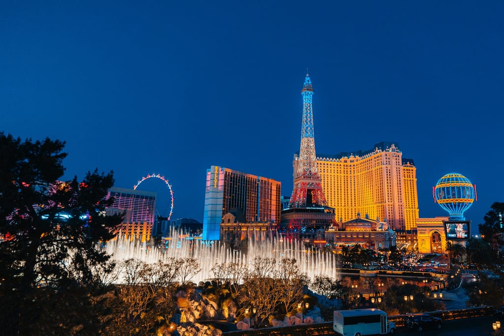 The Las Vegas Strip at dusk: the Bellagio fountains, the Paris hotel’s tower and balloon, and the High Roller wheel behind them
