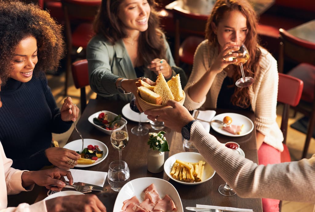 Friends sharing bread, food and conversation around a restaurant table
