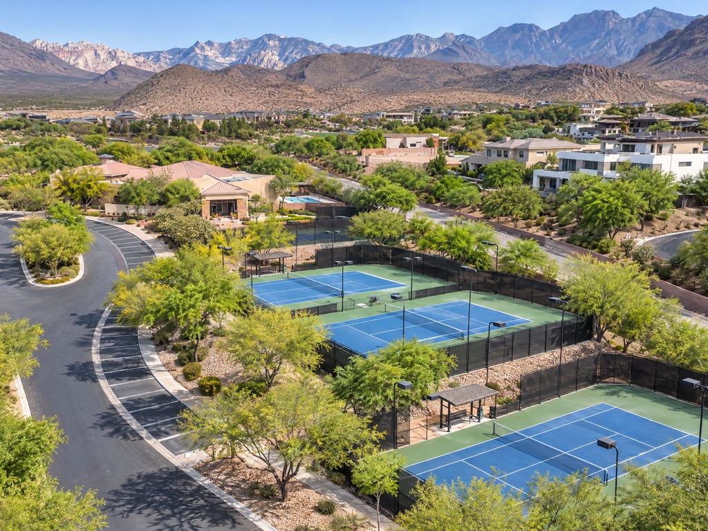 Tennis courts among desert trees and homes, below bare mountain ridges