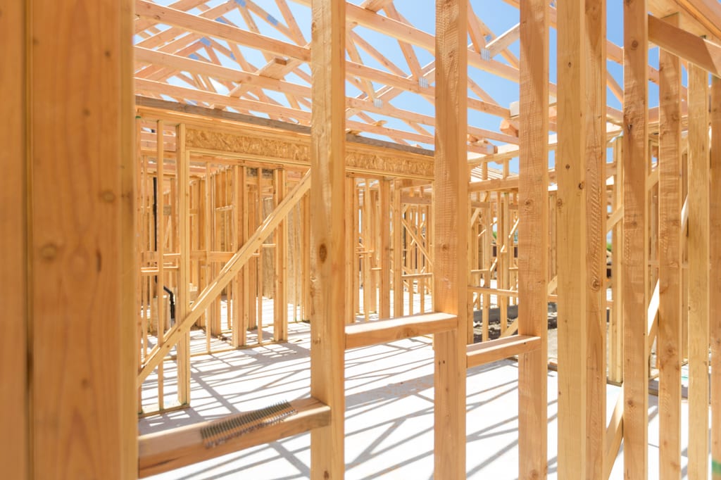Sunlight falling through the wooden framing of a home under construction.