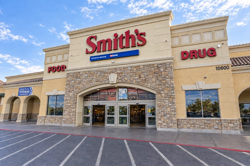 The entrance of a Smith’s Food and Drug store, a stone-clad archway over glass doors under the street number 10600, facing an empty striped parking lot.