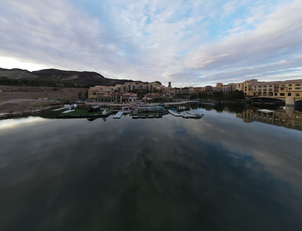 Clouds reflected in Lake Las Vegas beside waterfront buildings, docks and boats